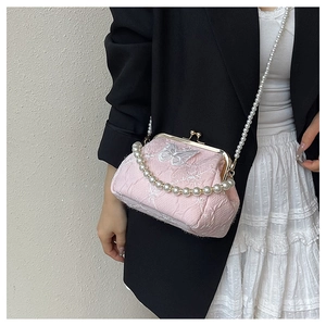 Detail of pink embroidered fabric bag with butterfly patterns and vintage gold clasp