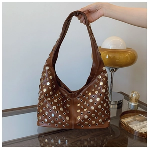 Détail d'un sac seau marron orné d'œillets argentés et de rivets au style rock chic
