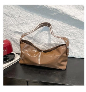 Detail of caramel brown glossy shoulder bag showing silver rivets and high-shine leather texture
