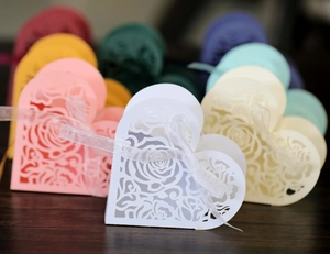 Detail of laser-cut rose hollow pattern on heart-shaped wedding favor box with ribbon