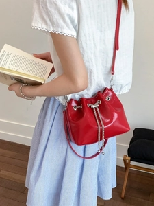 Sac seau rouge avec cordon chaîne argentée et bandoulière porté par un mannequin