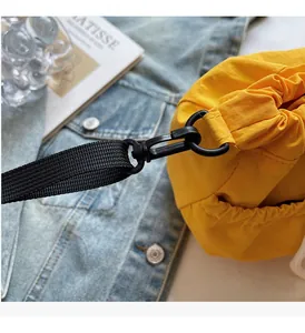Detail of durable black hook and strap on bright yellow nylon bucket shoulder bag