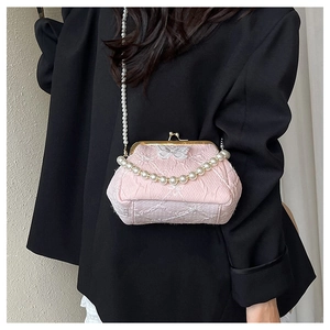 Close-up of pink lace handbag with pearl handle and metal clasp in a stylish studio shot