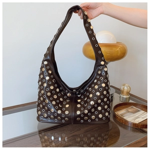 Détail du sac seau en cuir marron foncé avec des rivets argentés et des œillets