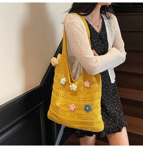 Dettaglio borsa tote in maglia gialla con fiori 3D all'uncinetto su abito nero