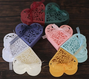 Detail of colorful heart-shaped laser cut favor boxes with roses and organza ribbons