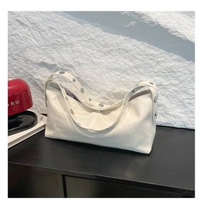 Detail of cream underarm bag featuring glossy finish and silver metal grommet strap decor