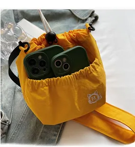 Detail of yellow nylon bucket bag with large exterior pockets and cat embroidery