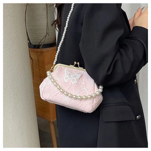 Detailed view of pink fabric crossbody bag featuring butterfly embroidery and pearl strap