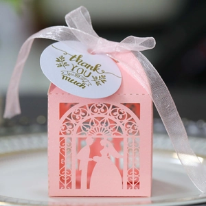 Macro detail of laser-cut pink wedding favor box with bride silhouette and silk ribbon