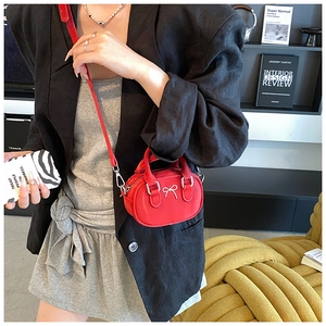 Close-up of a mini red leather bowling bag with silver bow accent and detachable strap