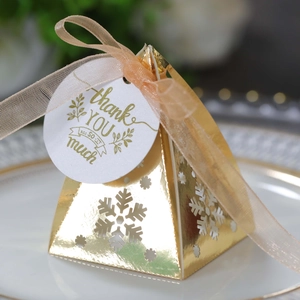 Detail van een gouden geschenkdoos met uitgesneden sneeuwvlokken en een organza lint strik