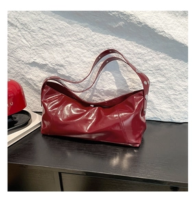 Detail of burgundy patent leather shoulder bag with silver rivet studs on the strap
