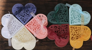 Flat lay of colorful heart-shaped laser-cut wedding favor boxes with ribbon bows