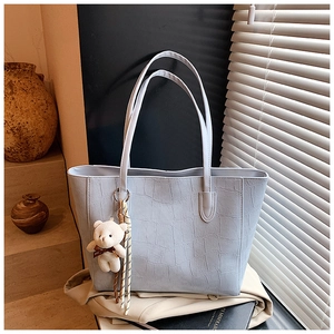 Detail of light blue crocodile texture tote bag with a cute white bear pendant charm