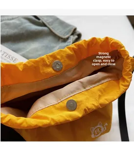 Close-up of secure magnetic snap closure on a yellow canvas bucket bag for easy access