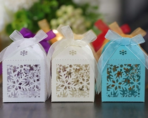 Detail of laser-cut snowflake hollow candy boxes with elegant ribbons for party favors