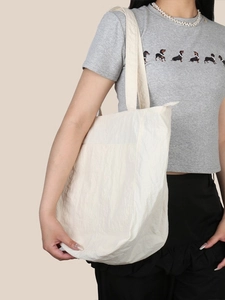 Grande borsa tote minimalista bianco avorio in tela testurizzata indossata da modella