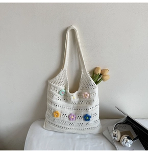 Detail of hand-crocheted white tote bag featuring colorful 3D knitted floral decorations