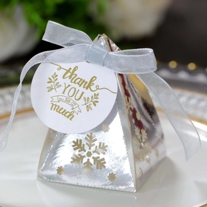 Detail van zilveren piramide geschenkdoos met sneeuwvlok uitsparing en bedankje met lint