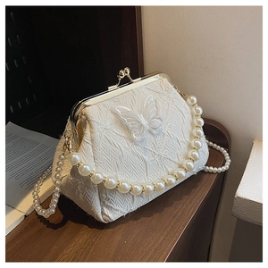 Detail of white quilted bag featuring a butterfly applique and pearl handle chain