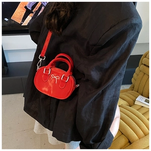 Detail of red patent leather mini bowling bag with silver bow and crossbody strap