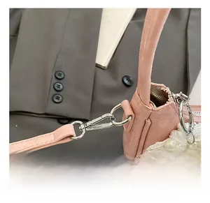 Dettaglio del gancio argentato su borsa rosa a pieghe con ciondolo in pizzo e perle