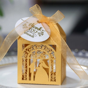Detailed close-up of golden hollow bride and groom wedding favors box with gold ribbon