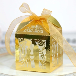 Detailed laser-cut gold wedding favor box with heart silhouette and golden organza ribbon