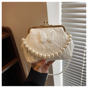 Detail of white vintage bag with butterfly embroidery and elegant pearl handle