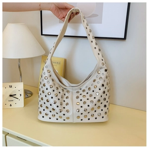 Détail du sac hobo punk blanc cassé avec rivets argentés et découpes rondes évidées