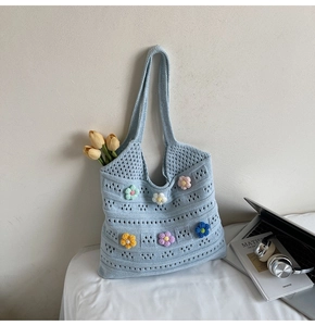 Close-up of light blue knit handbag featuring colorful handmade 3D crochet flowers
