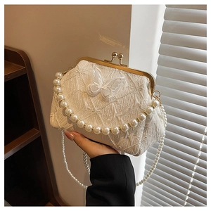 Detail of white lace handbag featuring 3D butterfly accents and pearl chain strap