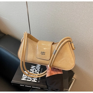 Vue détaillée du sac baguette beige brillant avec logo métallique et poignée élégante