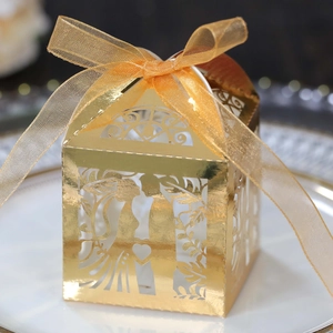 Detailed view of laser-cut gold wedding favor box with silhouette and organza ribbon