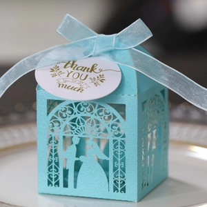 Detail of light blue laser-cut wedding favor box with ribbon and thank you tag
