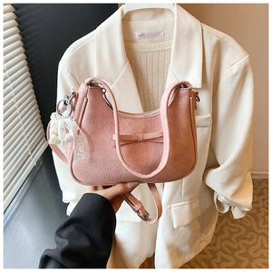 Rosa Plissee Hobo-Tasche mit Schleife und Perlen-Spitzen-Anhänger vor weißem Anzug