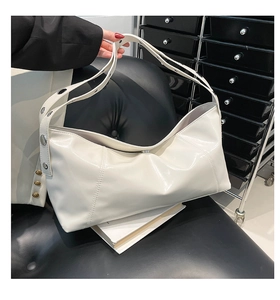 Detail view of glossy white shoulder bag with decorative stitching and rivet strap