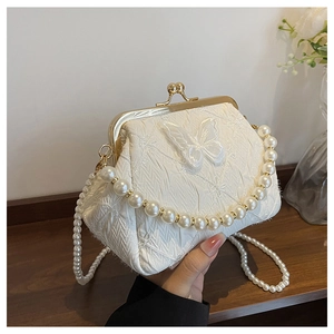 Detail of elegant pearl evening bag featuring fabric pleats and mesh butterfly applique
