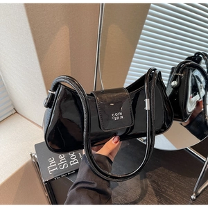 Détail du sac baguette en cuir verni noir avec logo argenté et finition brillante élégante