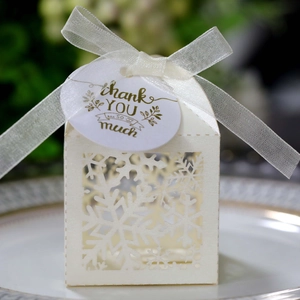 Close-up of laser-cut snowflake gift box with white ribbon and thank you tag
