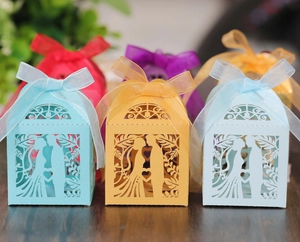 Macro detail of laser-cut wedding favor boxes with bride and groom silhouette and ribbon