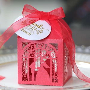 Close-up of red laser-cut wedding candy box with bride silhouette and silk ribbon