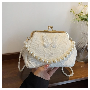 Detail of cream pleated handbag with lace butterfly applique and pearl chain strap
