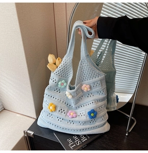 Dettaglio della borsa tote in maglia azzurra con fiori 3D colorati e trama traforata