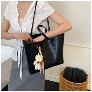 Black crocodile embossed tote bag with teddy charm and silk scarf shown on shoulder