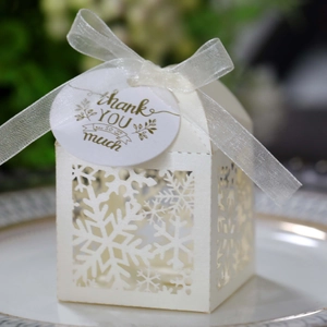 Close-up of white snowflake laser cut gift box with white organza ribbon and thank you tag