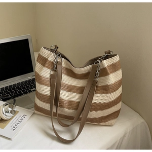 Détail du sac cabas tissé avec des poignées en cuir marron et des détails de chaîne en métal