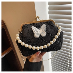 Detail of black textured evening bag with lace butterfly, gold clasp and pearl handle