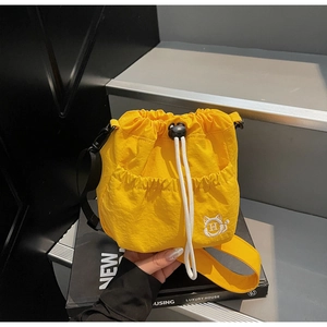 Detail view of yellow nylon bucket bag with white drawstring and cat head embroidery
